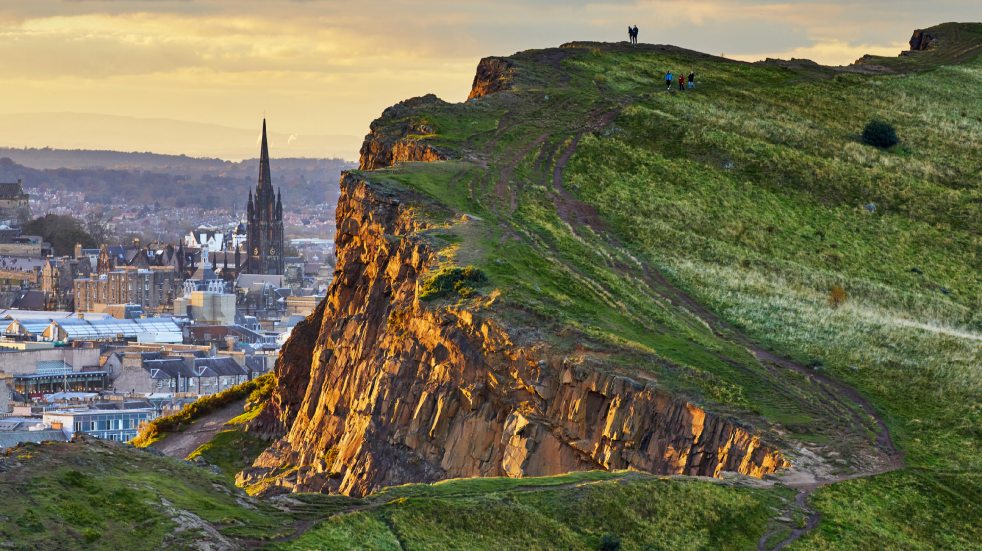 People walking up hillside with city views